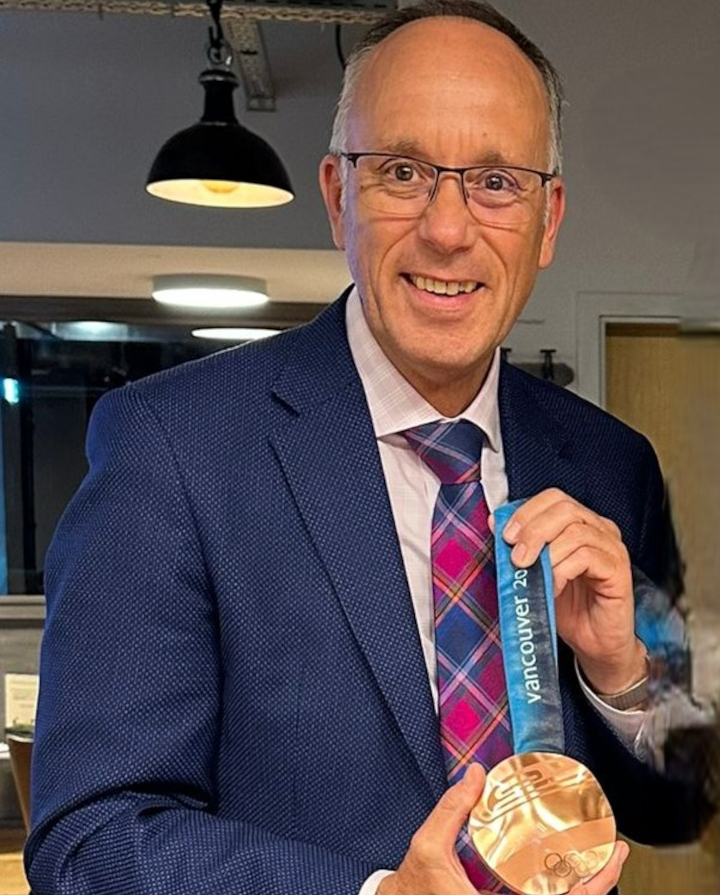 Auf dem Foto ist Foto ist Oliver Fuchs im Jahr 2024 mit der original Medaille von Kati Wilhelm aus 2010, Vancouver.