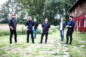 Die Band The Complement Club posiert auf einer grünen Wiese