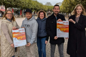 (v.l.) Inga Schaper (Teamleitung Eventmanagement, Stadtmarketing Holzminden GmbH), Marc Gonzaga (Foodtruck „3 Stars“), Isabell Adam (Teamleitung PR & Marketing, Stadtmarketing Holzminden GmbH), Benjamin Beineke (2. Vorsitzender des Werbekreis Holzminden e.V.) und Sarah Krause (Marketing und PR Stadtwerke Holzminden GmbH) stehen auf dem Marktplatz Holzminden und halten gemeinsam zwei Veranstaltungsplakate zum Herbstglühen in den Händen.