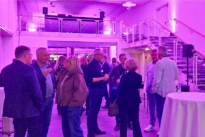 Violett ausgeleuchtetes Foyer der Stadthalle Holzminden und mehrere Menschen, die Grüppchen zusammenstehen und sich unterhalten.