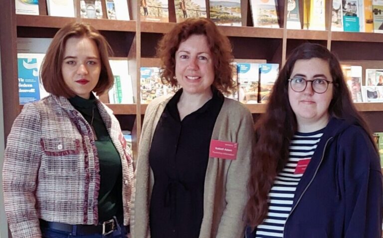 von links: Viktoria Raab, Isabell Adam und Franziska Salowsky stehen vor der Prospektwand in der Tourist-Info.