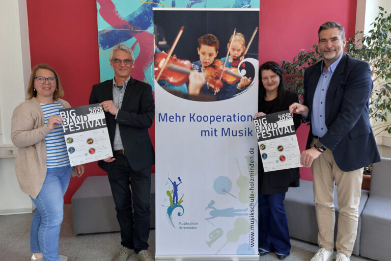 Die Organisatoren und Holzmindens Bürgermeister posieren mit den Veranstaltungsplakaten vor einem Roll-Up der Musikschule Holzminden.