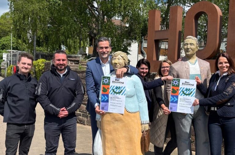 Das Organisationsteam bestehend aus Stadtverwaltung und Stadtmarketing Holzminden posieren mit den Lechner-Figuren am Weserkai und dem Veranstaltungsplakat zum Ehrentag.