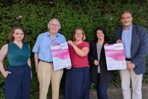 Viktoria Raab und Karlheinz Klammt (Kulturverein Holzminden e.V.), Inga Schaper und Michaela Reinecke-Koller (Stadtmarketing Holzminden GmbH) sowie Bürgermeister Christian Belke posieren mit Veranstaltungsplakaten im Grünen.